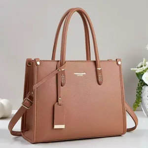 Detail of caramel leather handbag with lychee texture and gold metal hardware accents