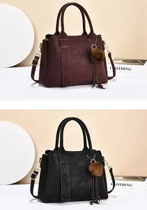 Gros plan détaillé de grands sacs en cuir mat bordeaux et noir avec un pompon en fourrure