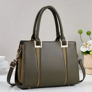 Detail der olivgrünen Handtasche mit gewebten Akzenten und goldfarbenen Metallbeschlägen