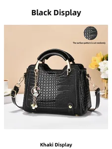 Detail of black faux leather bag with crocodile texture, gold hardware and pearl charm