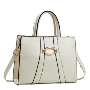 Minimalist cream leather handbag with black trim and elegant gold oval hardware detail