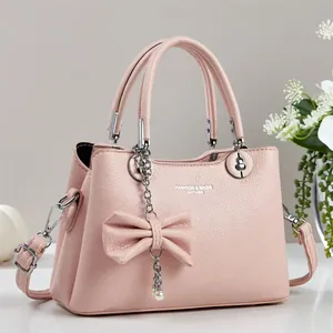 Détail d'un sac à main en cuir grainé rose clair avec nœud et décorations en perles