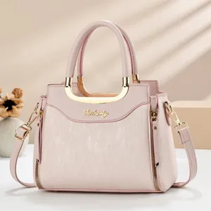 Détail du sac à main rose clair avec rayures verticales et logo en métal doré en U