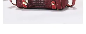 Close-up of crocodile pattern handbag with protective golden feet and pearl charm detail