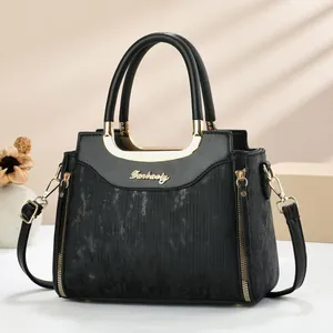 Détail du sac à main en cuir noir avec rayures texturées et poignées en métal doré