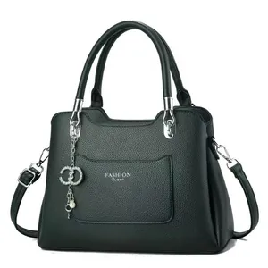 Detail of black lychee leather handbag with Fashion Queen text and pearl metal charm
