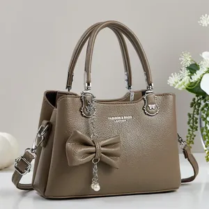 Braune Handtasche aus Litschi-Leder mit Schleifenanhänger und silbernen Griffen