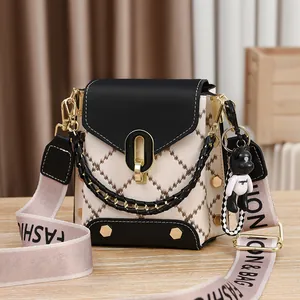 Sac bandoulière matelassé chic noir et crème avec large sangle et breloque en forme d'ours