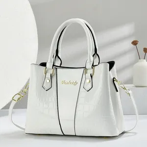 Detail of white handbag featuring crocodile texture, smooth lacquer, and gold hardware
