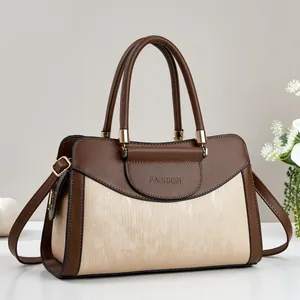 Detail of two-tone brown and beige PU leather handbag with gold metal hardware
