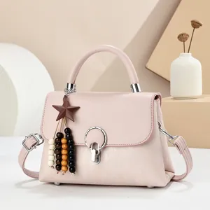Detail of pink leather handbag with silver rotary lock and colorful star bead pendant