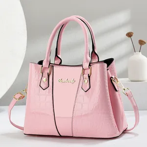Detail of pink faux crocodile leather stitching and gold Danbaoly metal logo on handbag