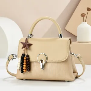Detail of beige flap handbag with vertical textures and gold circular metal lock