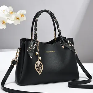 Elegante schwarze Handtasche aus Leder mit dekorativem Seidenschal und goldenem Anhänger