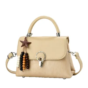 Classic beige crossbody flap handbag with textured pleats and star pendant detail
