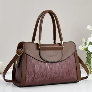Detail of elegant two-tone brown tote bag featuring textured panels and gold metal hardware