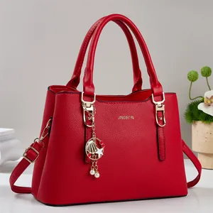 Détail du sac rouge à texture litchi avec dorures et pendentif en perles et nacre