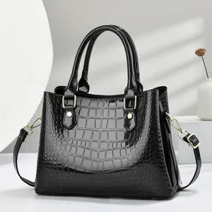 Detail view of black crocodile pattern patent leather handbag with glossy texture