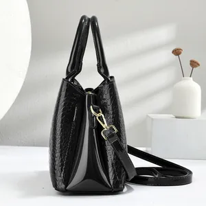 Macro shot of glossy black crocodile embossed leather and golden hardware on the handbag