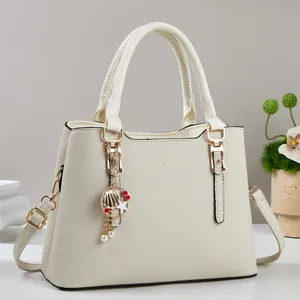 Détail du sac à main en cuir grainé avec pendentif doré et bandoulière amovible beige