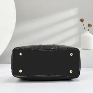 Detail of black faux leather handbag base with crocodile texture and gold protective studs