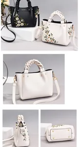 Detail of embroidered floral patterns, woven handles, and gold-tone hardware on women's bag