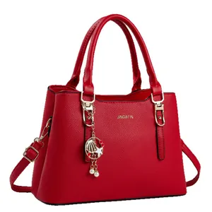 Sac à main classique en cuir rouge avec motif litchi, logo doré et pendentif coquillage