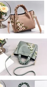 Detailed close-up of premium embroidered floral handbag with woven handle and gold rings