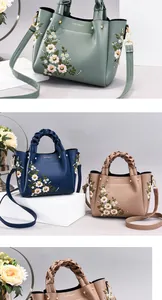 Detailed view of floral embroidery and woven handle on textured leather crossbody bag