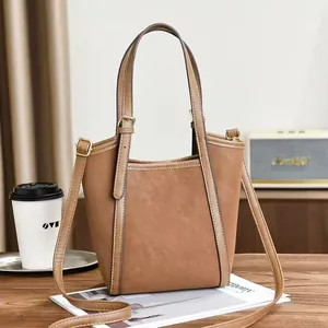 Borsa tote marrone in pelle sintetica con dettagli dorati su un tavolo di legno