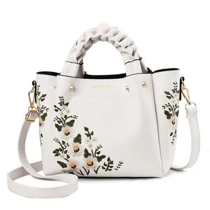 Elegant ivory faux leather tote with floral embroidery and woven handles