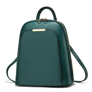 Detail of dark green leather backpack featuring gold hardware and smooth textured finish
