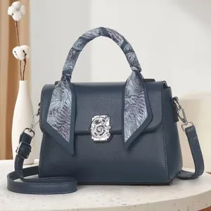 Detail of dark blue lychee leather handbag with silver floral clasp and decorative scarf