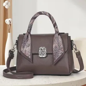 Detail of brown leather handbag with vintage G-lock, silk scarf, and adjustable strap