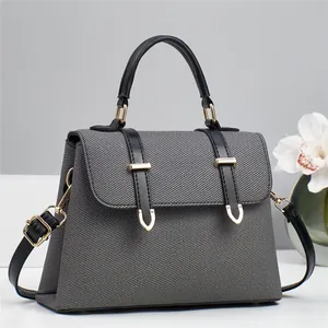 Detail of grey twill texture and black leather strap with gold hardware on a handbag