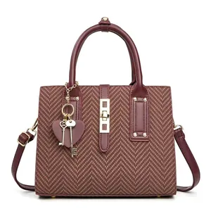 Elegant burgundy crossbody handbag with textured fabric and gold heart pendant