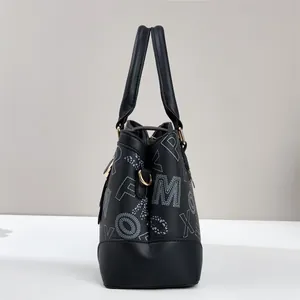 Detail of lychee pattern leather texture and gold hardware on black letter print handbag