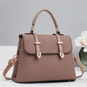 Detail view of the brown textured fabric handbag featuring gold buckles and elegant leather straps
