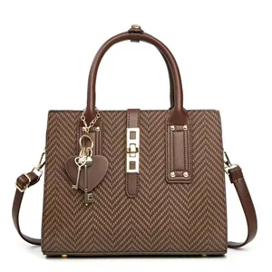 Brown herringbone shoulder bag with gold heart charms and adjustable strap on white background