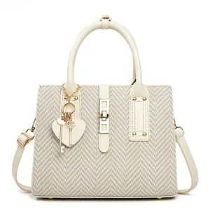 Detailed shot of beige V-quilted texture, gold lock, and heart charm on luxury handbag