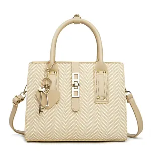 Detail of cream woven handbag featuring golden twist lock and heart-shaped charm