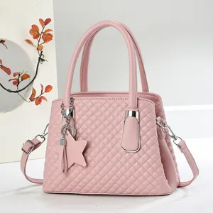 Elegant pink quilted handbag with star charm and top handles in office setting