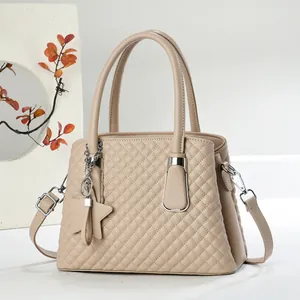 Close-up of beige quilted handbag with U-shaped metal buckle and star pendant detail