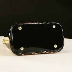 Detail of leopard print shell bag with black patent leather base and golden protective studs
