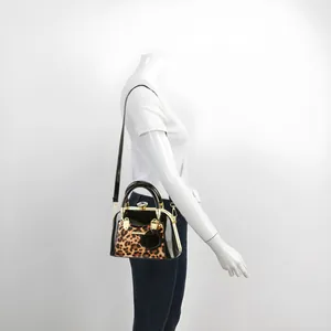 Detail of leopard print shell bag with crystal buckle and rose charm on a model