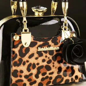 Close-up of leopard print shell bag with gold hardware, crystal clasp and rose pendant