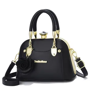 Detail of black faux leather shell bag with gold frame and diamond-shaped clasp