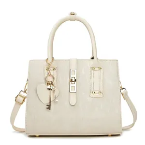 Dettaglio borsa tote beige con chiusura rotante argentata e pendente a cuore
