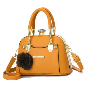 Close-up of yellow shell-shaped handbag with golden metal frame and diamond clasp detail