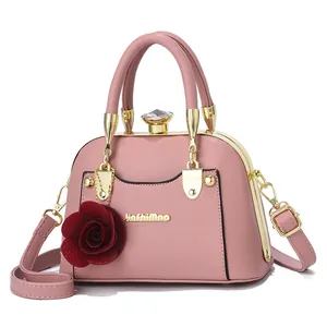 Detailed front view of pink shell bag with golden metal frame and red rose pendant